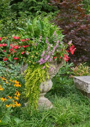 Stone bench and stone urn with annual flowers in the landscape.