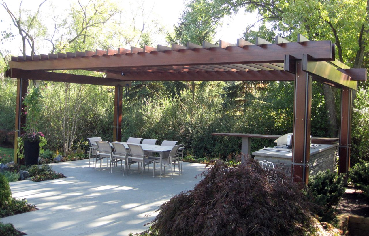 Modern wood and steel pergola with casual dining and a grill center.
