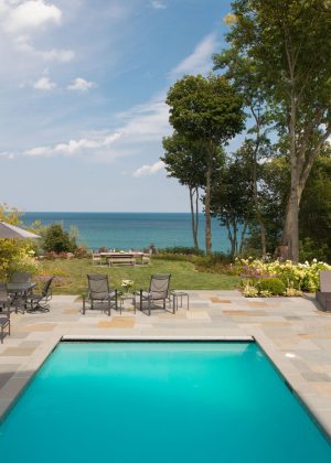 View to Lake Michigan overlooking a turquoise colored pool and bluestone patio.