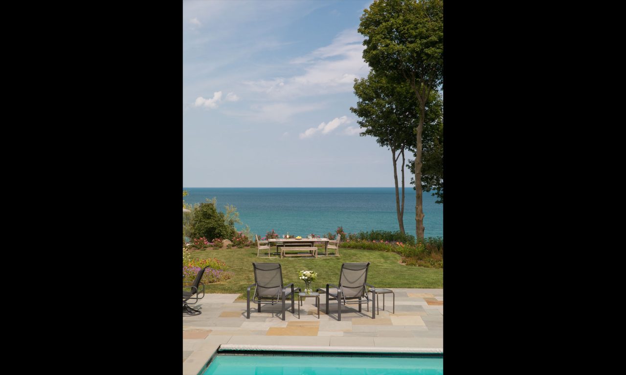 Serene view to Lake Michigan looking over a grass lawn with outdoor dining furniture.