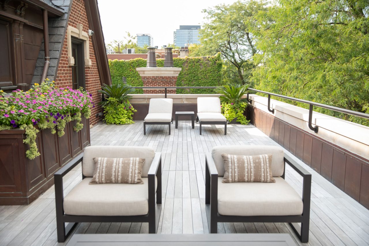 Chicago rooftop garden with flower planters, palm trees, and neutral colored outdoor furniture.