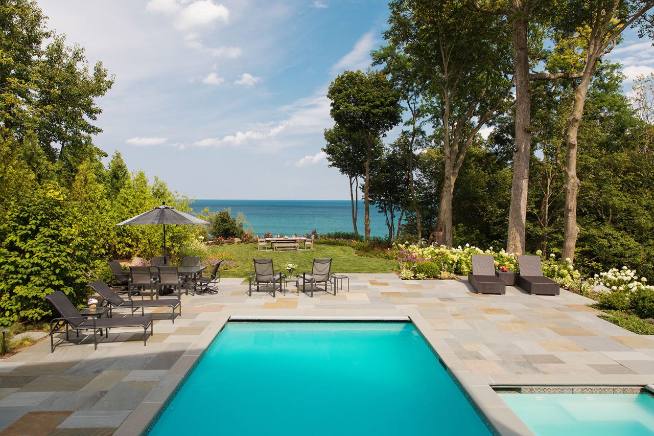 View to Lake Michigan overlooking a turquoise colored pool and bluestone patio.