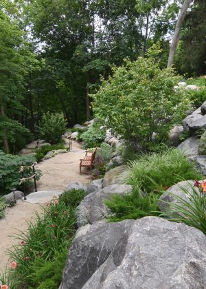 Bluff path with granite boulders, wooden bench, and rope railing