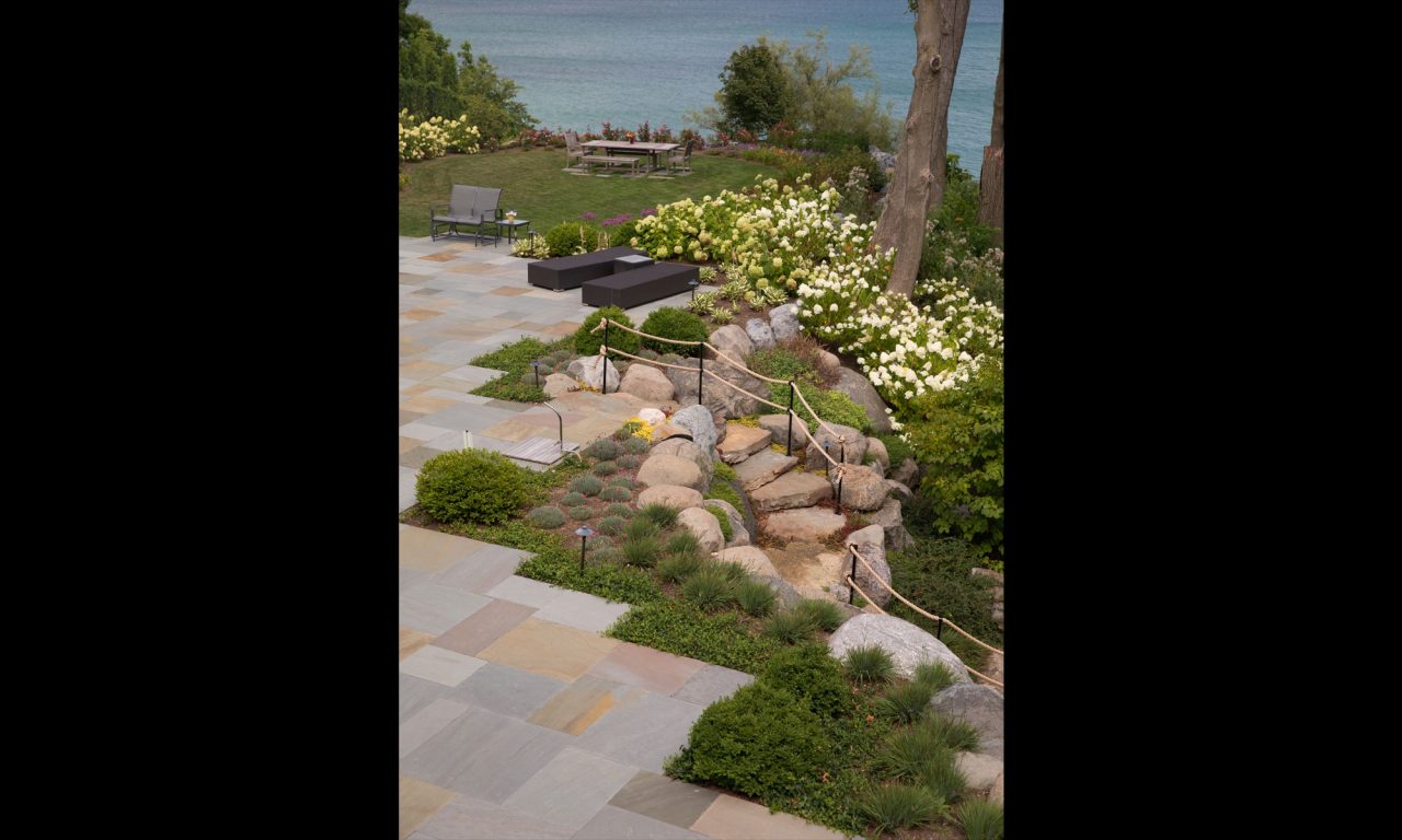 Stone deck overlooking Lake Michigan and bluff with granite boulder steps and rope railing