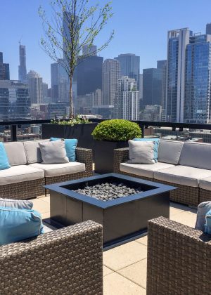 Chicago rooftop garden with black metal fire pit, potted trees and bushes