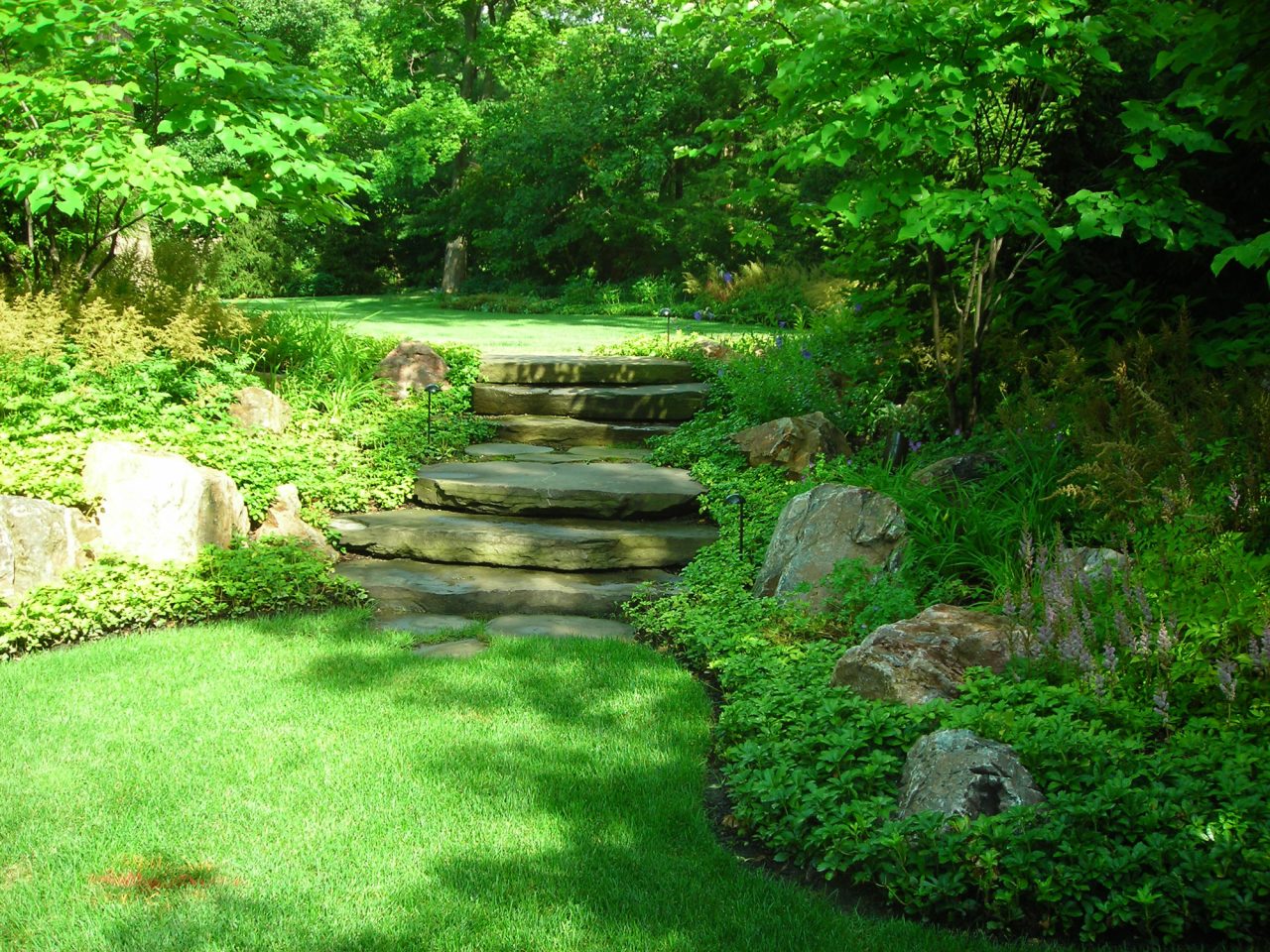 Fieldstone slab steps with boulder outcroppings leading to freshly mowed lawn