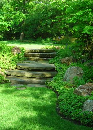 Fieldstone slab steps with boulder outcroppings leading to freshly mowed lawn