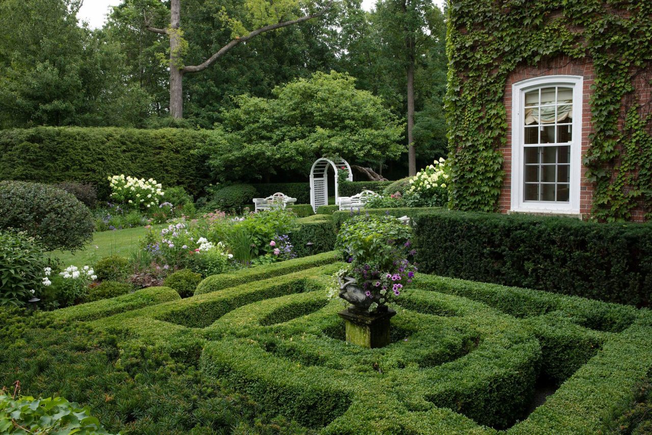 English, boxwood parterre garden accented by lead urn with lush florals