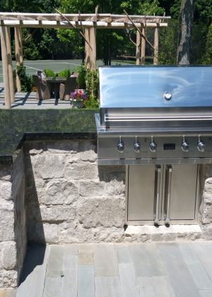 Outdoor kitchen grill structure wrapped in hardscape with granite countertop
