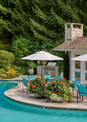 Waterfall cascading into pool with outdoor seating surrounded with bright annuals