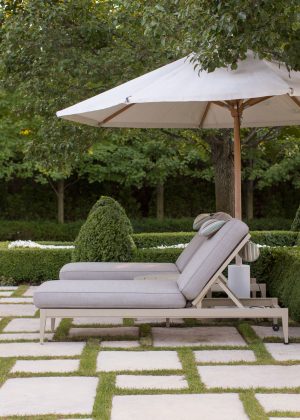 Stepper in-lawn terrace by pool with boxwood hedging and chaise lounges