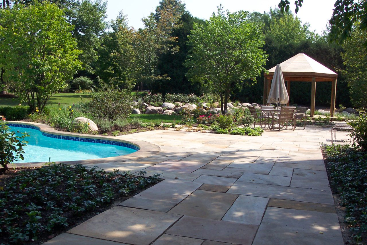 Crab orchard stone pool deck featuring wood pergola