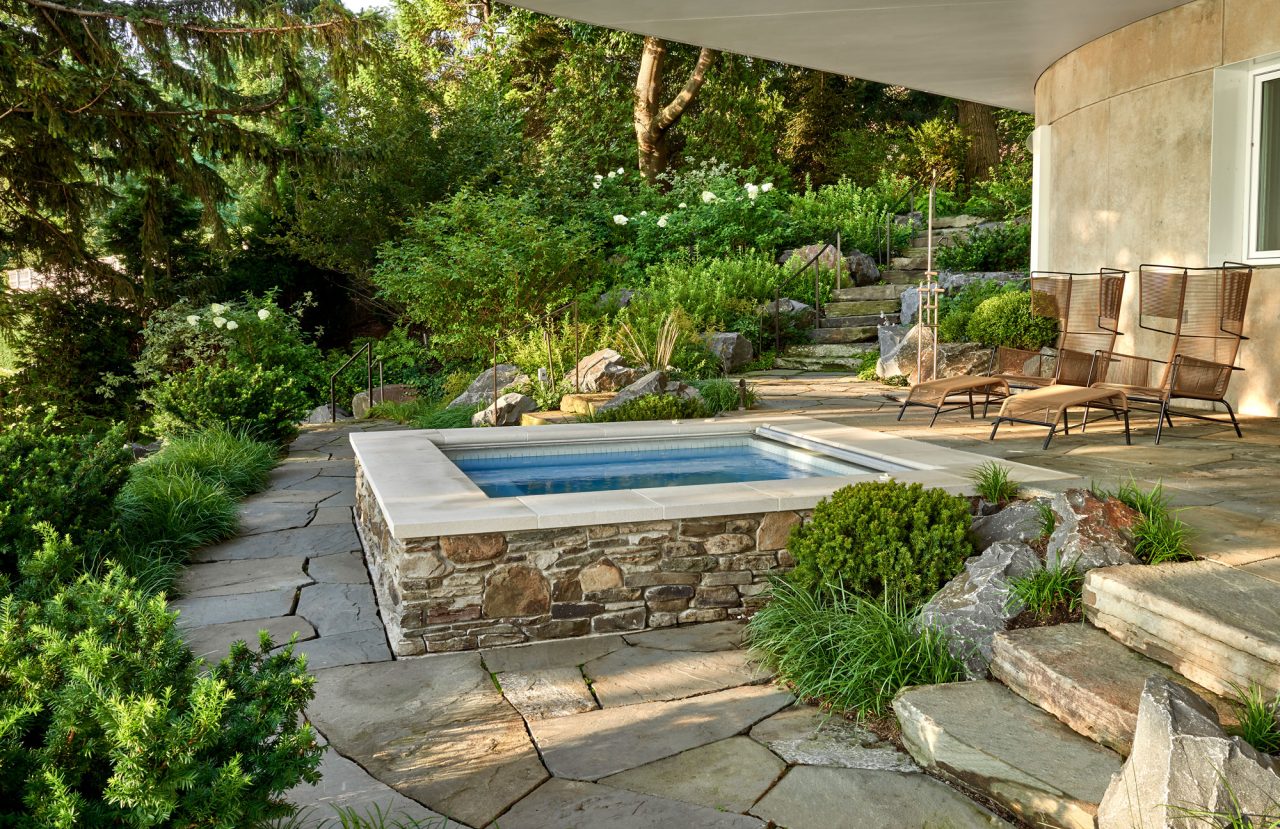 Spa tucked in naturalistic garden setting with lush planting and irregular hardscape.