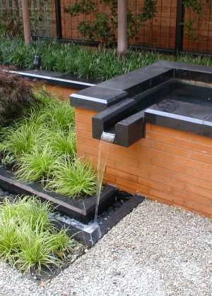 Modern brick and marble trough fountain with Japanese inspired planting
