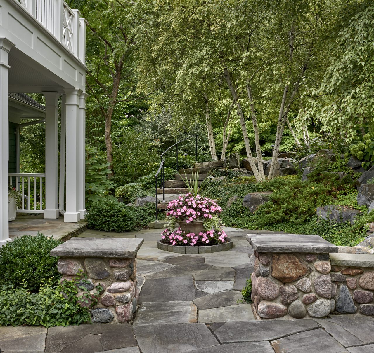 Stone entrance feature planted urn, flagstone steps, and natural border