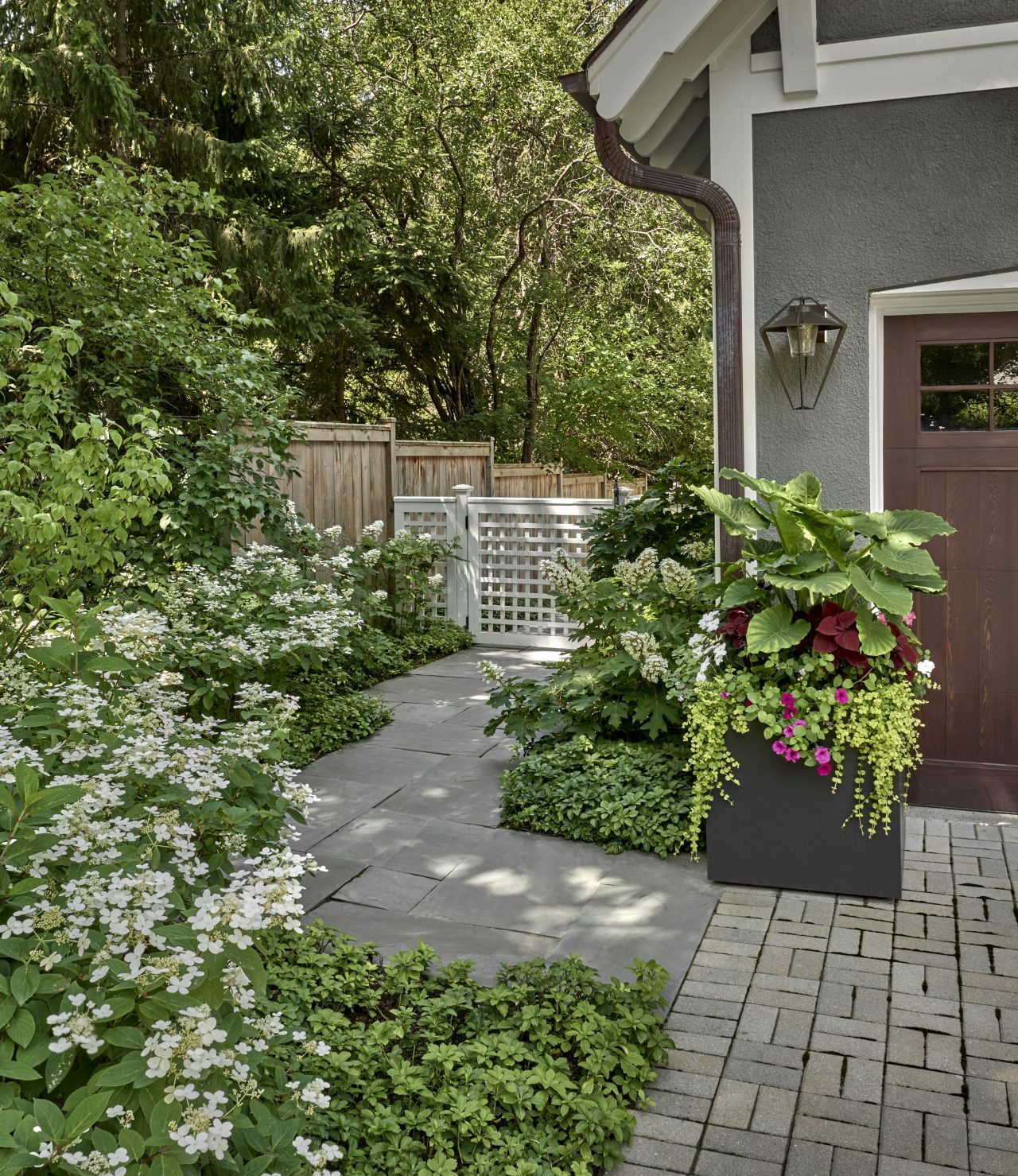 Annual containers, brick paver driveway, stone path
